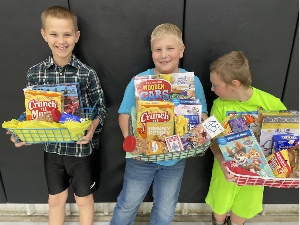 Three young boys holding baskets of food in front of a black wall