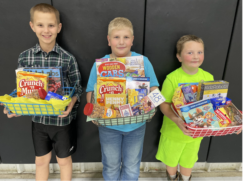 Three young boys holding baskets of food in front of a black wall