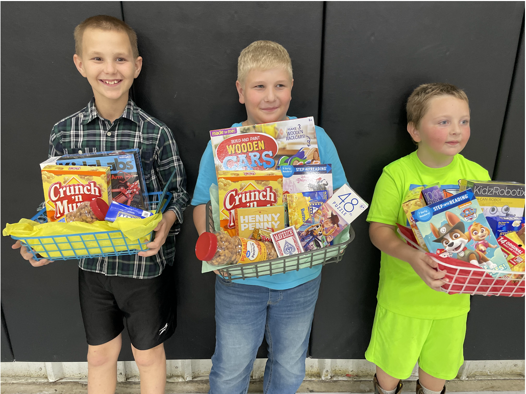 Three young boys holding baskets of food in front of a black wall