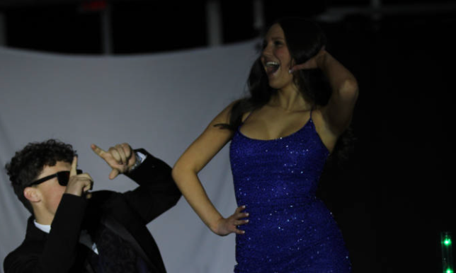 A man and woman in blue attire gracefully dancing together at a formal event.