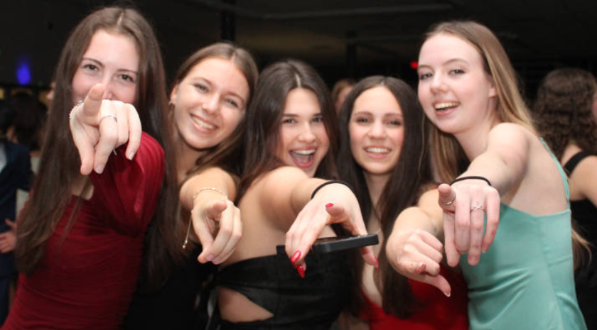 A joyful group of young women smiling and posing together for a picture at a lively party.