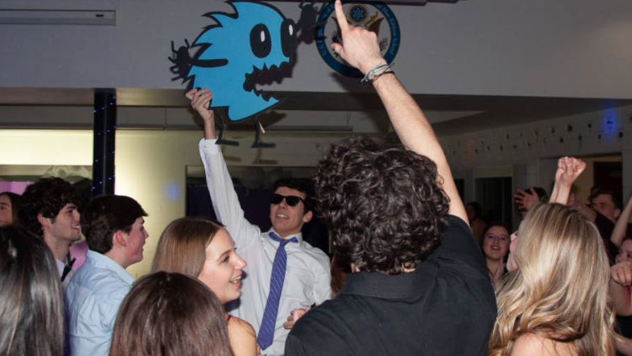 People mingling at a party with a blue bird artwork displayed in the background.