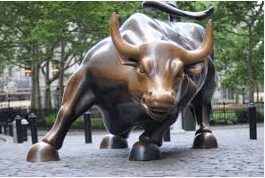 A bronze bull statue stands proudly in front of a majestic building, exuding strength and elegance.