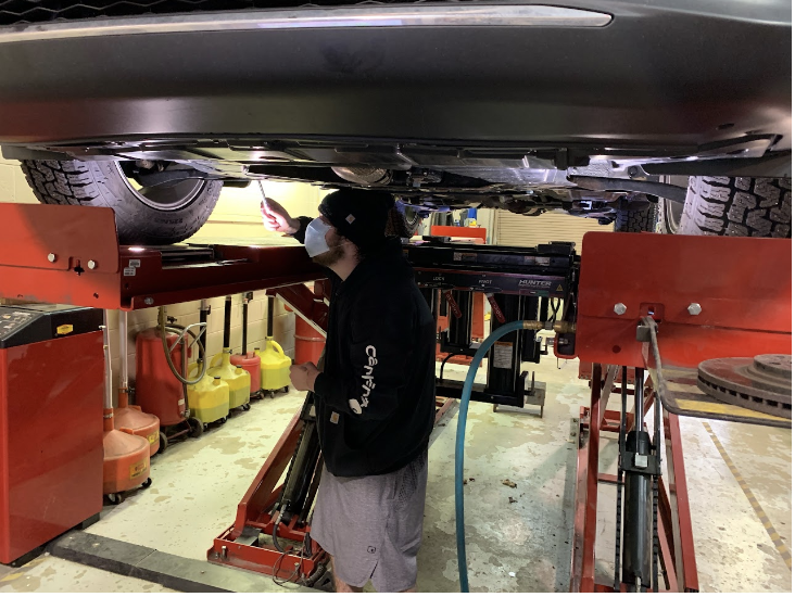 Student underneath elevated car