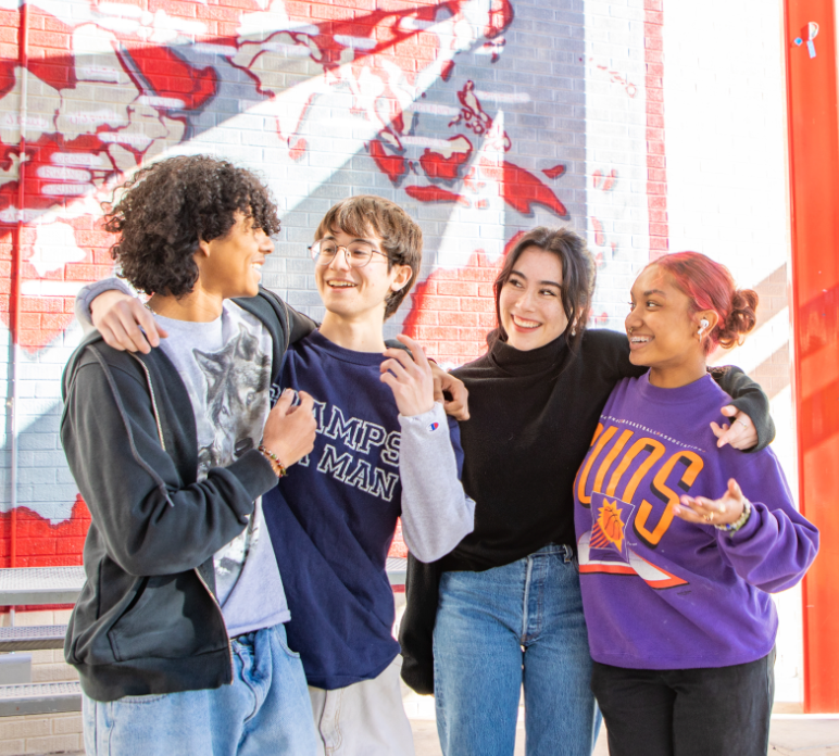 4 students smiling and talking to each other.