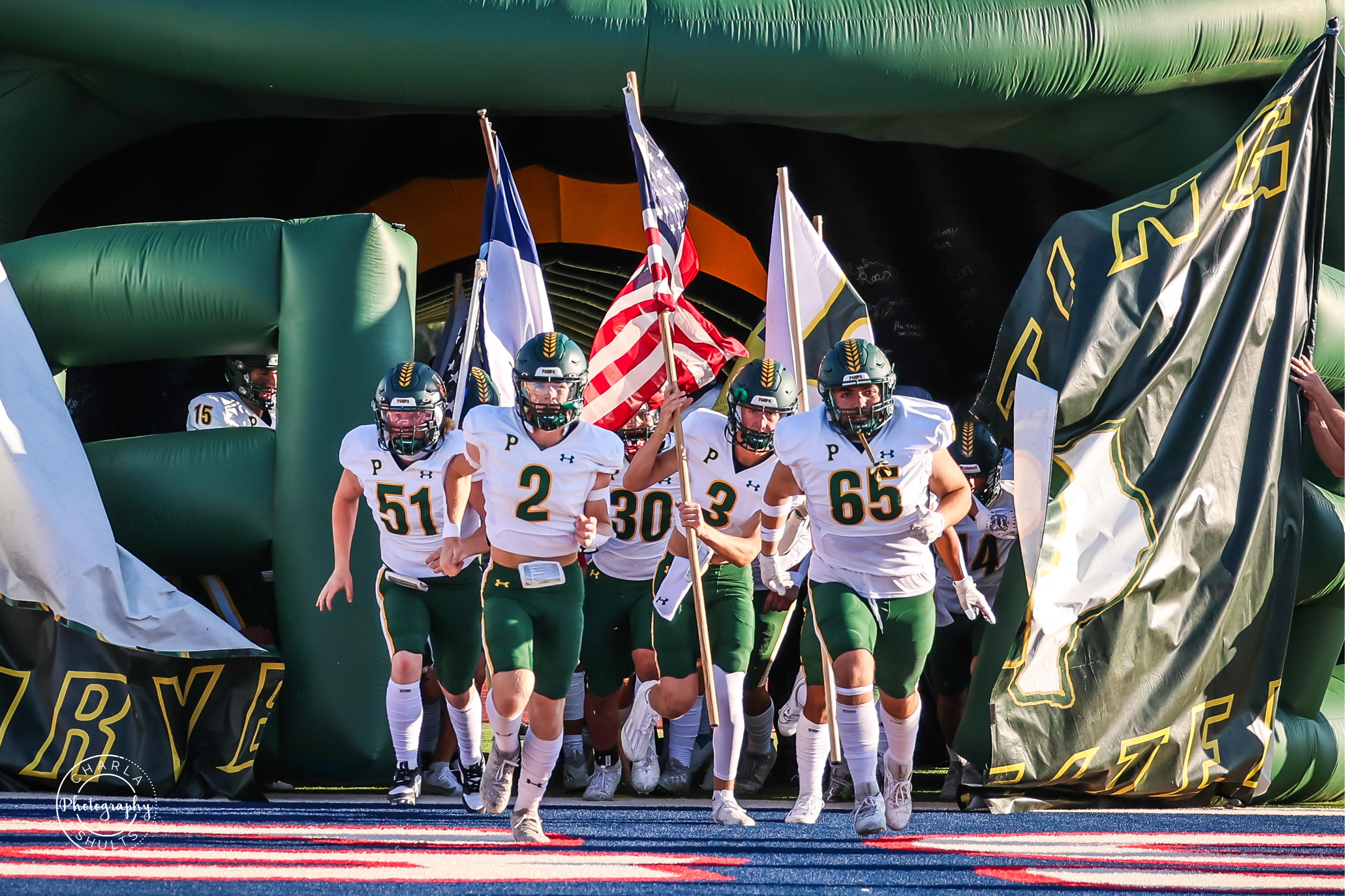 Pampa Harvester Football players running onto field with flags