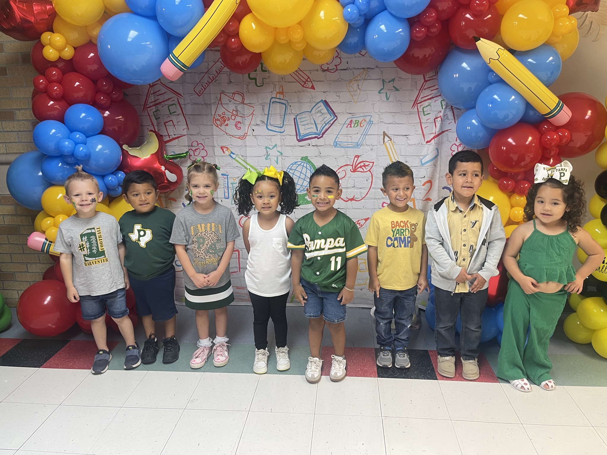 students standing together under a brightly colored balloon arch