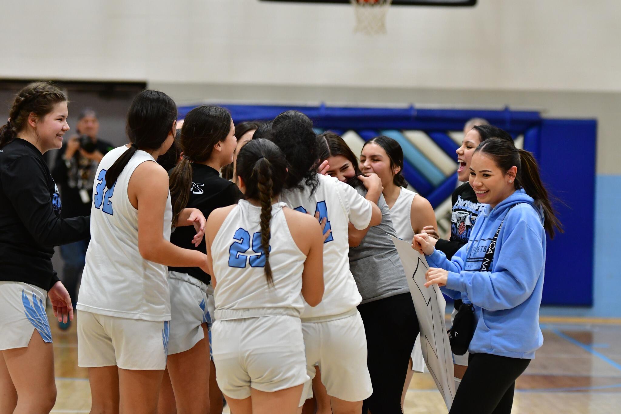 A group of young women standing around each other on a basketball court
