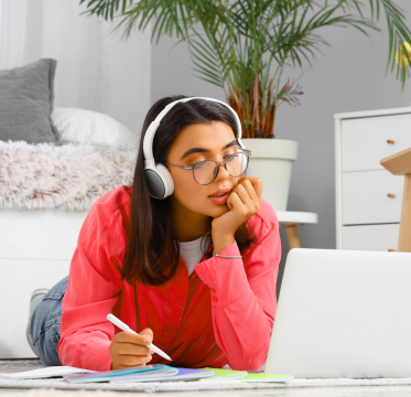 girl wearing headphones while sitting on the floor working on laptop