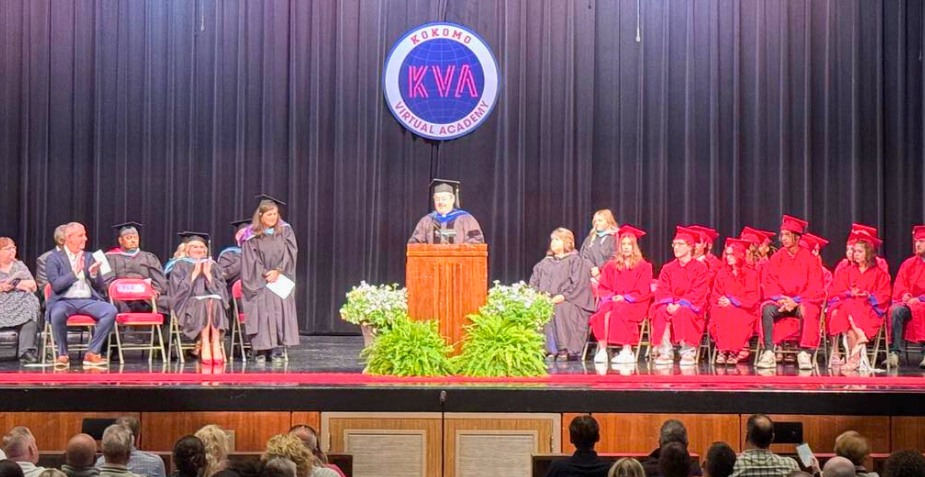 graduation commencement students wearing caps and gowns sitting on stage