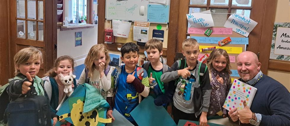 Students take a picture with their principal, with drawn images in the background