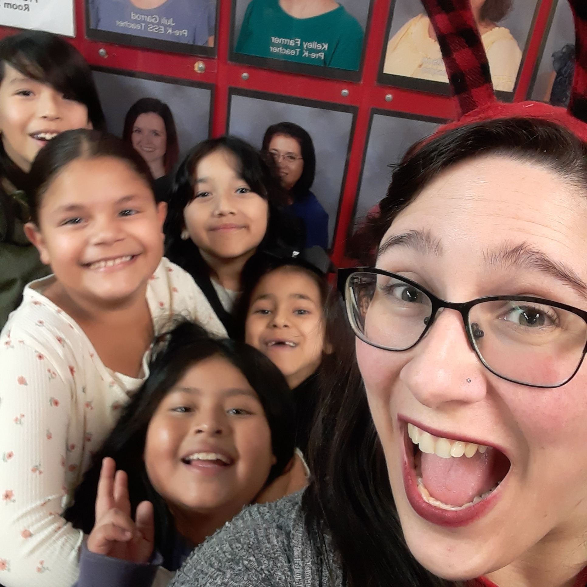 Teacher smiling with students behind her