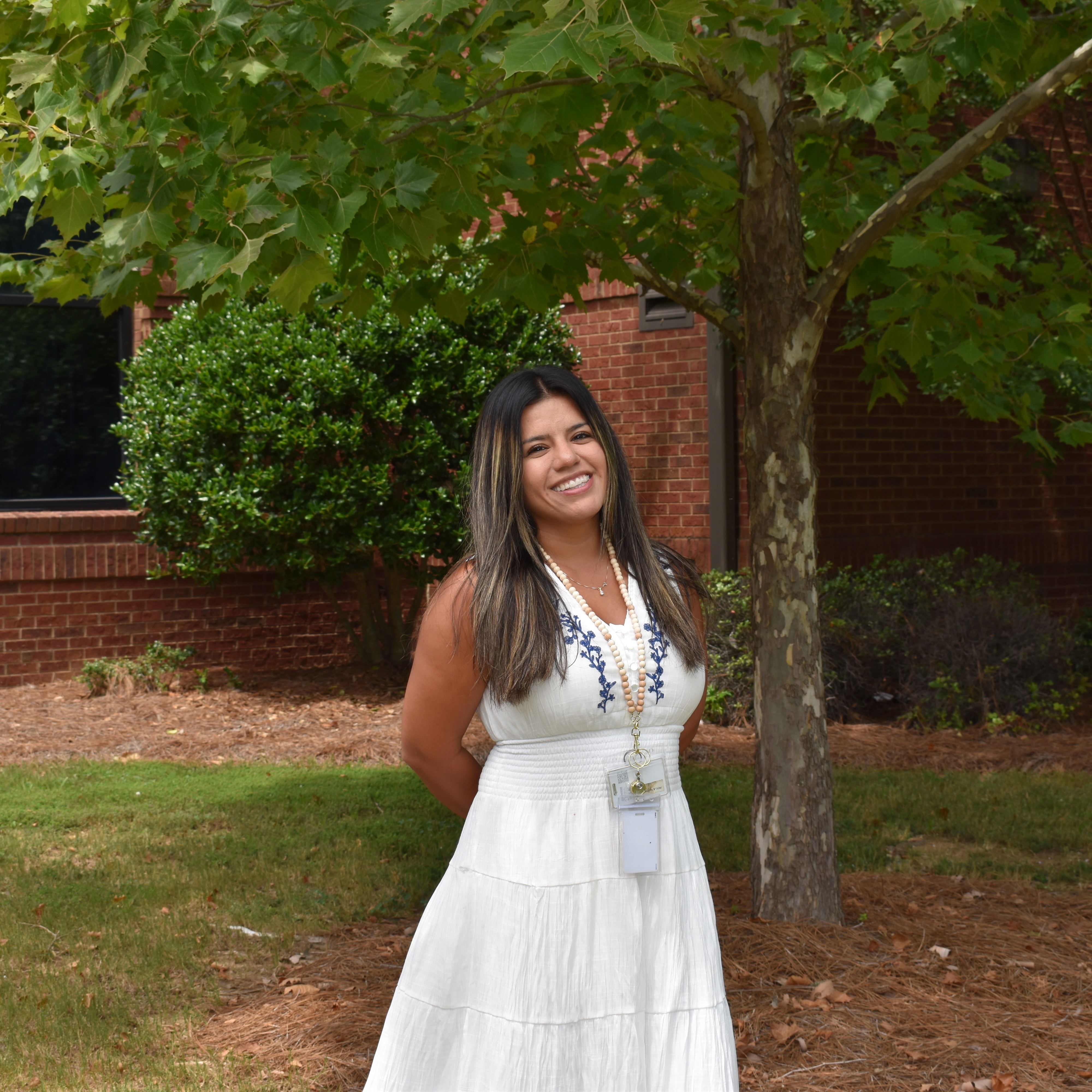 Female standing in front of tree smiling at camera