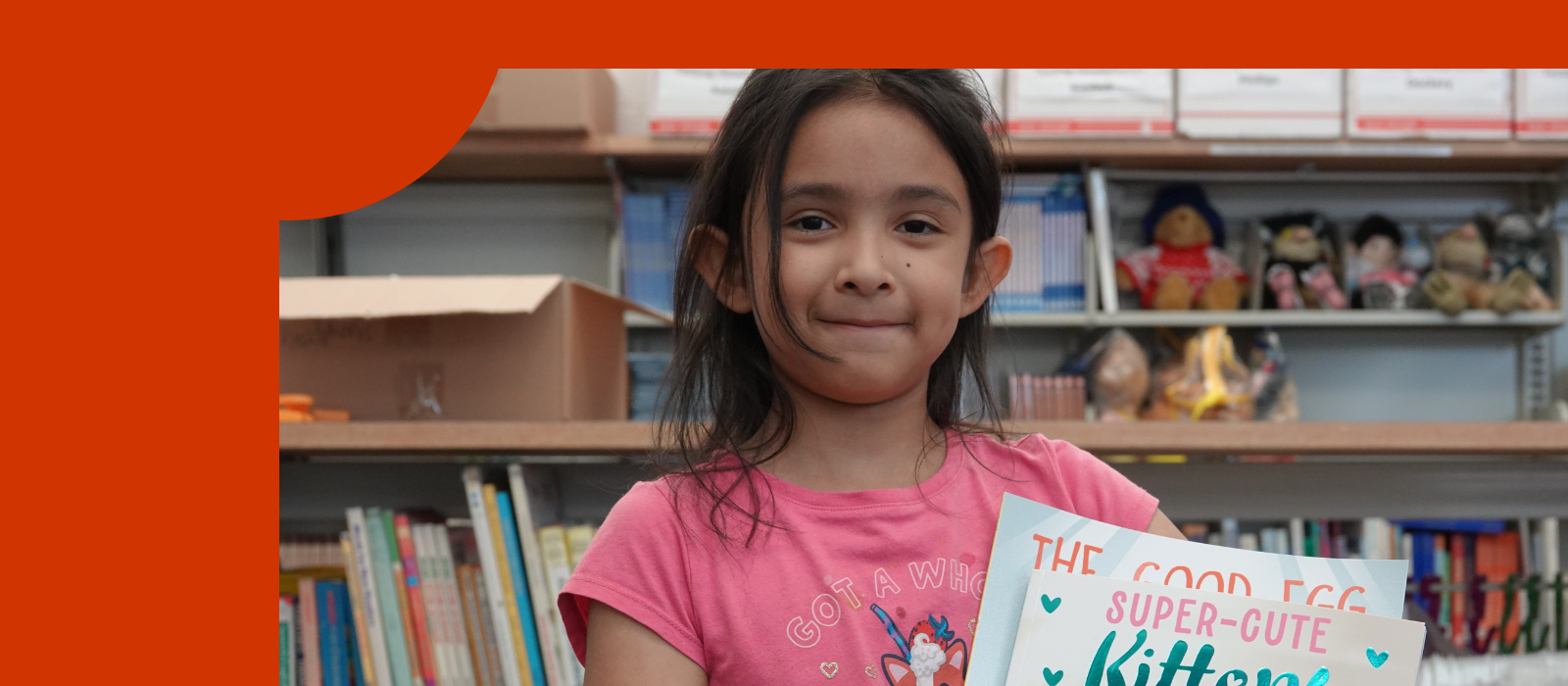 A girl wearing pink is holding a book