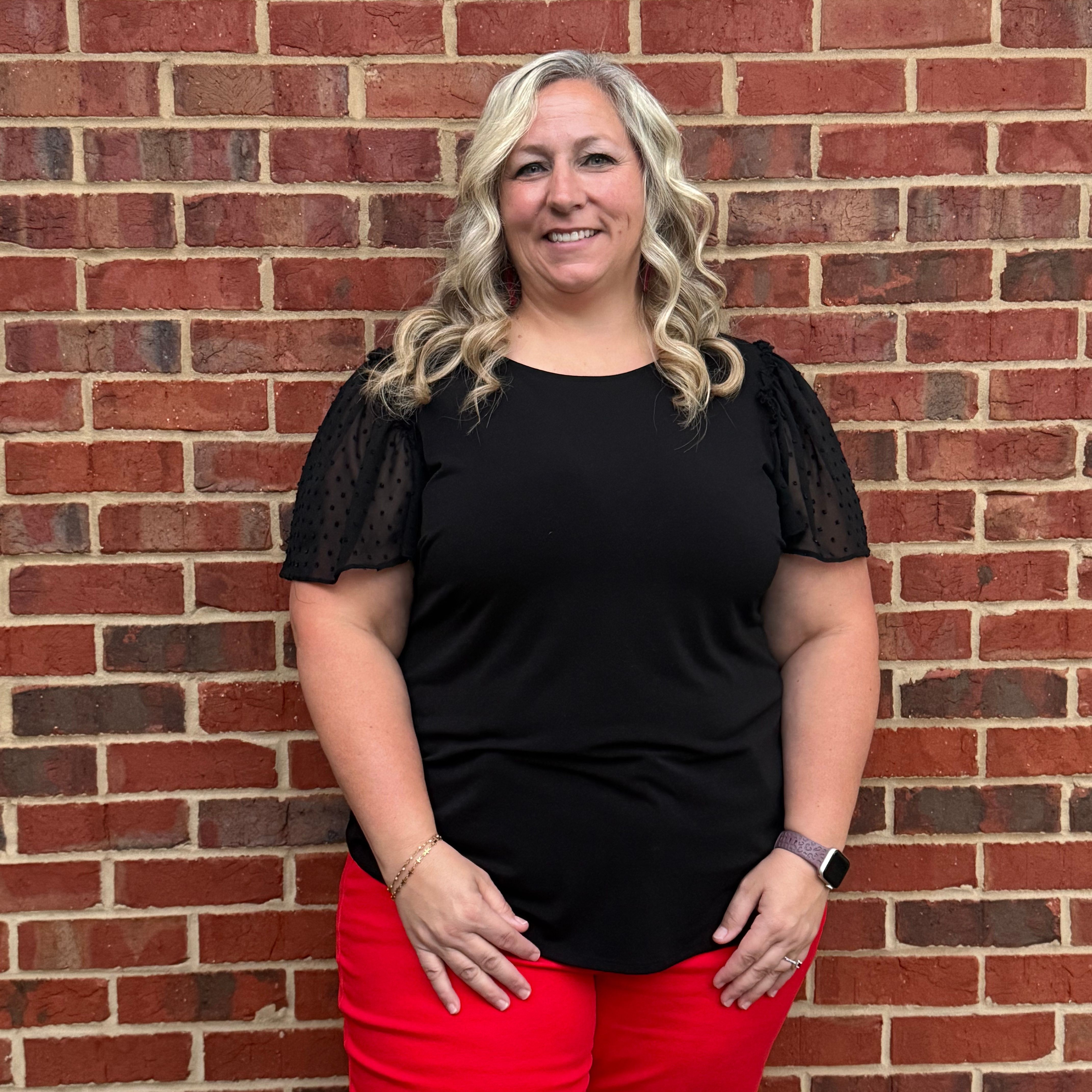 Teacher standing in front of a brick wall