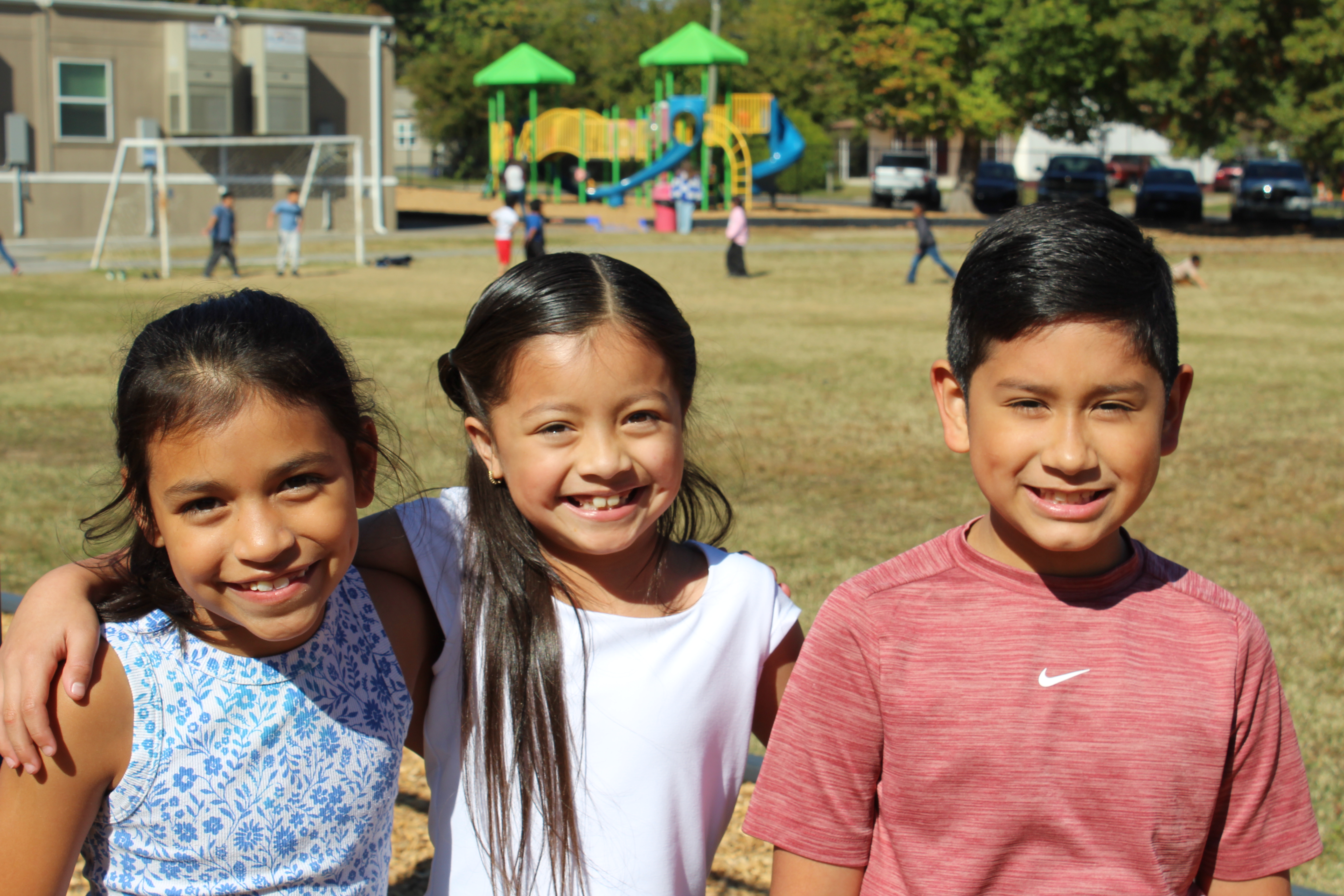 2 girls and 1 boy smiling on playground