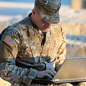 a soldier works on a laptop