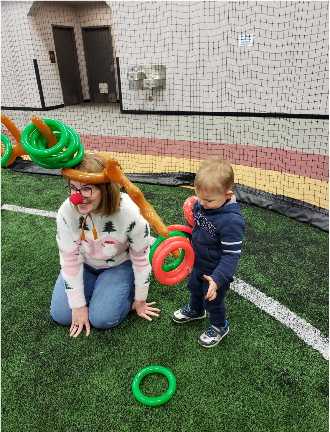 A woman and child joyfully playing with rings on a field, creating a heartwarming and playful scene