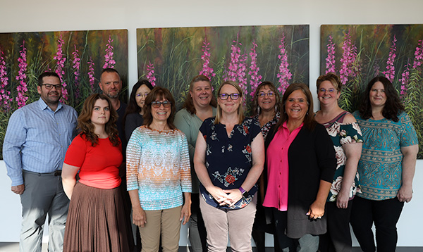 A diverse group of people standing in front of colorful paintings at an art gallery.