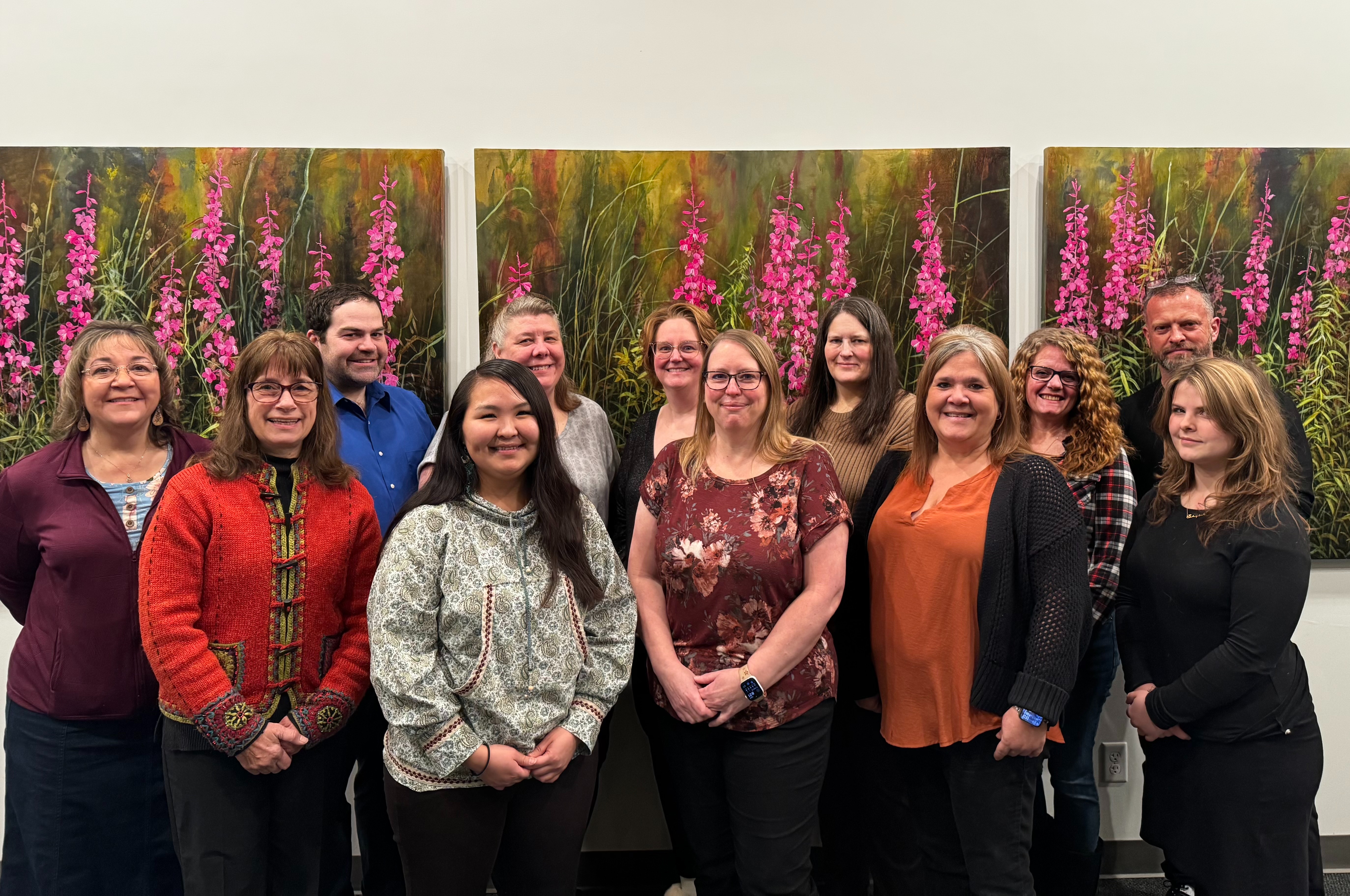 A diverse group of people standing in front of colorful paintings at an art gallery.