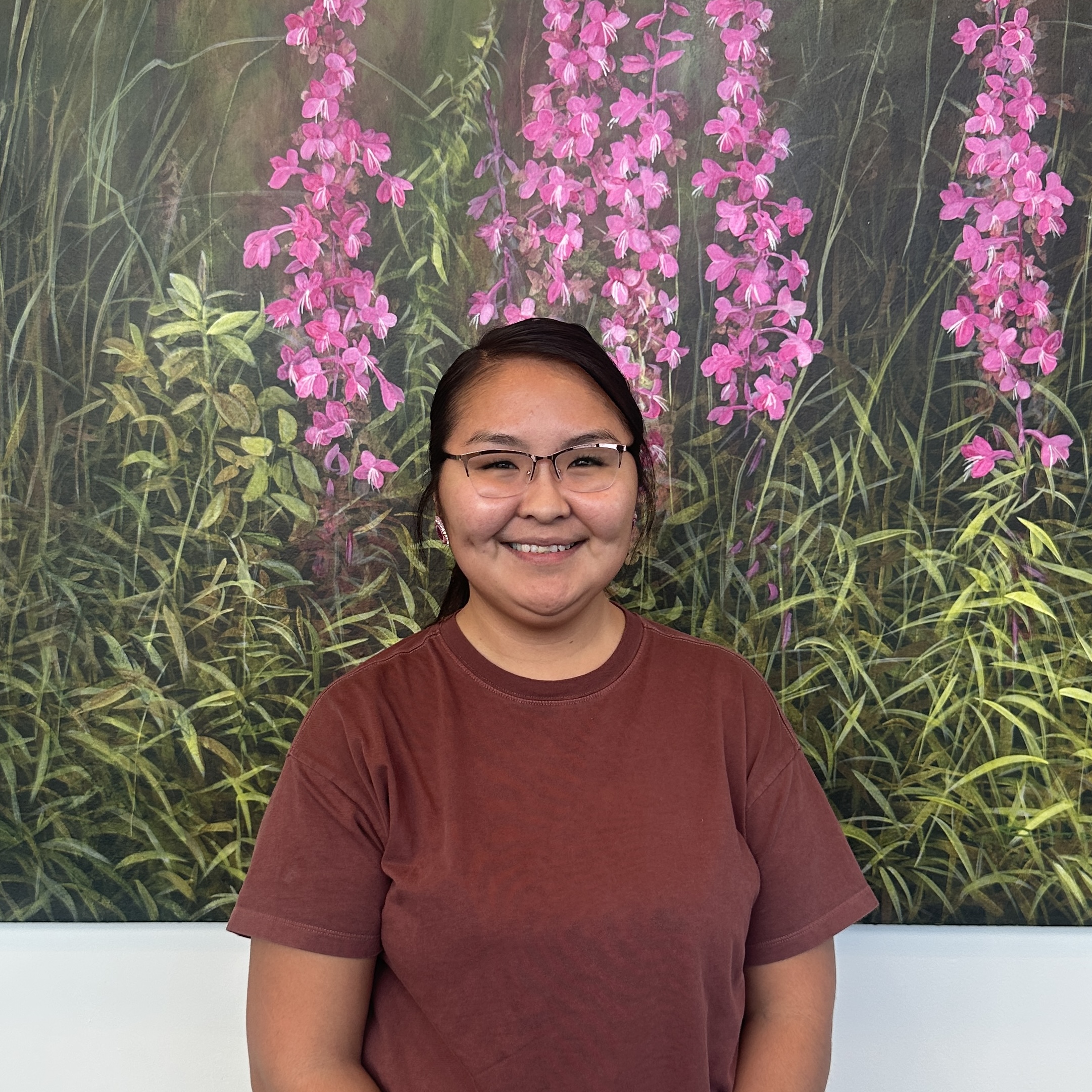 Thomasina standing in front of picture of fireweed