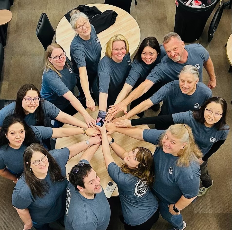 A diverse group of people standing in front of colorful paintings at an art gallery.