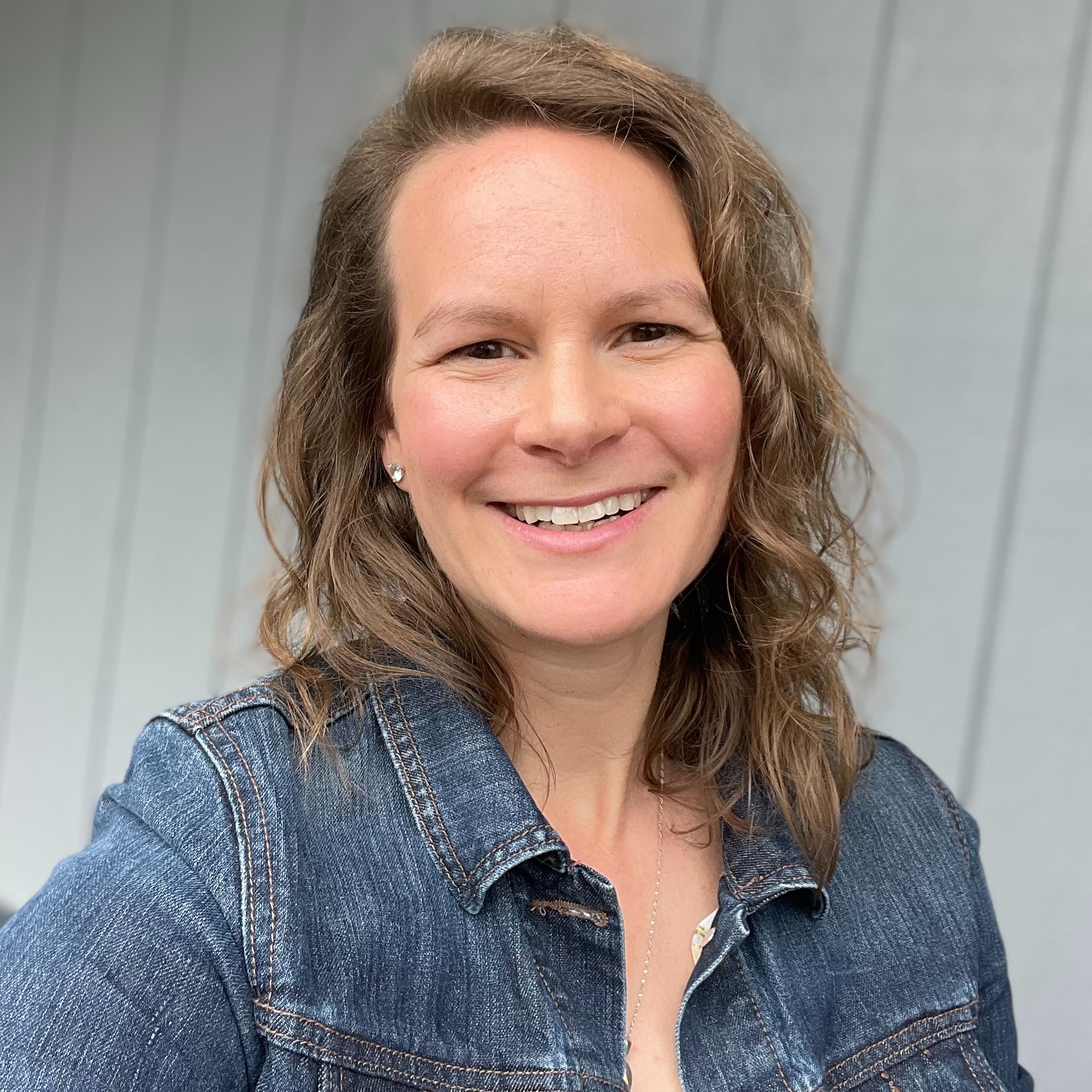 A woman with short hair wearing a blue jacket.