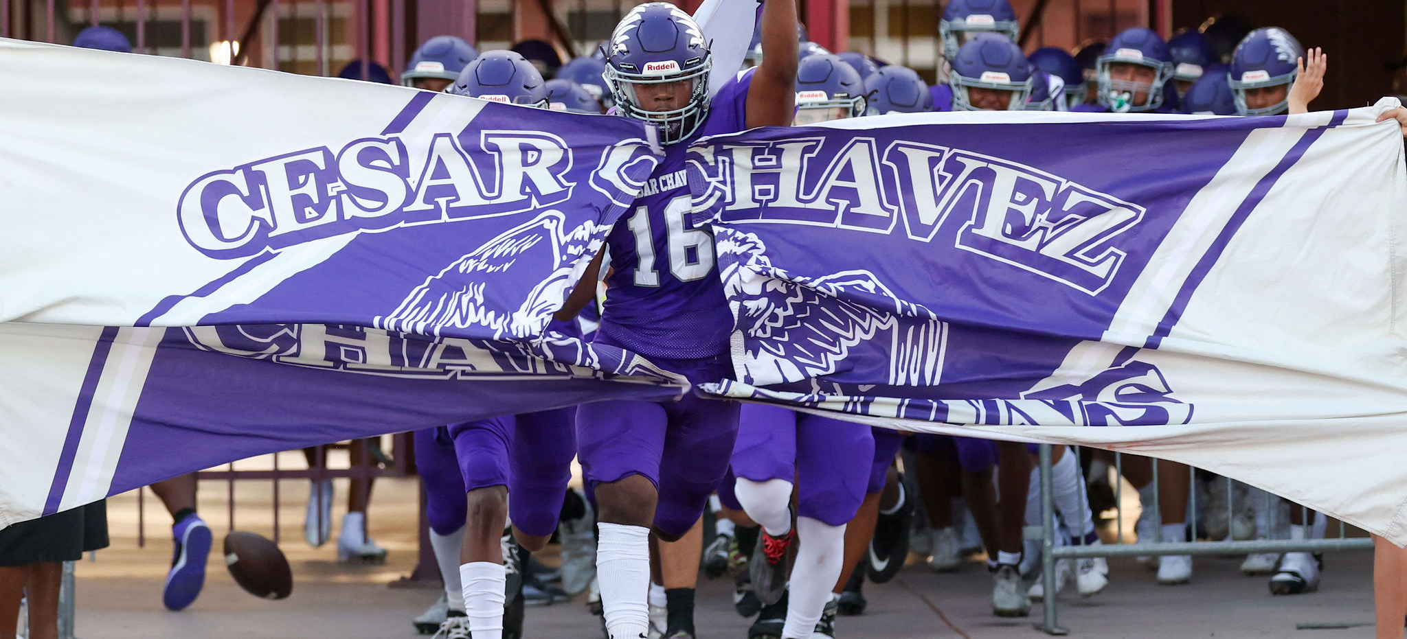 Football players running through a sign