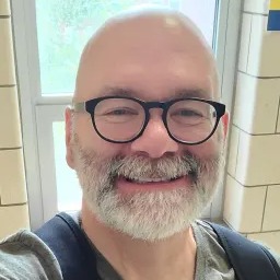 An image of a bald man wearing glasses and sporting a beard.