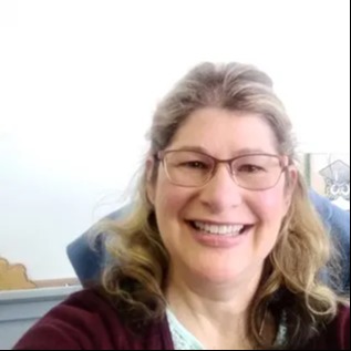 A smiling woman in glasses and a red sweater poses for a photo.