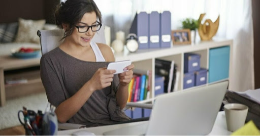 stock photo of lady on her phone in front of a laptop