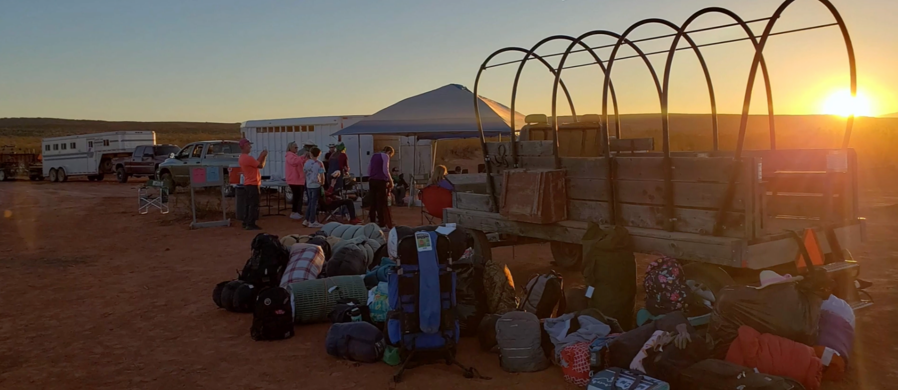 students camping in desert near covered wagon