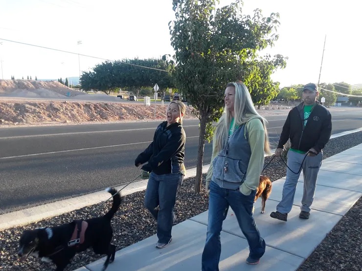 parents and a dog walking on the side walk