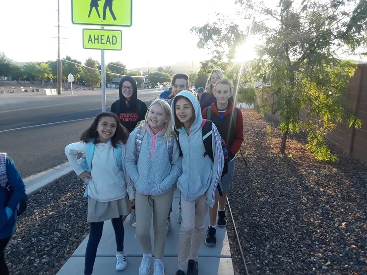 students posing on the side walk at the ride is a students walking sign 