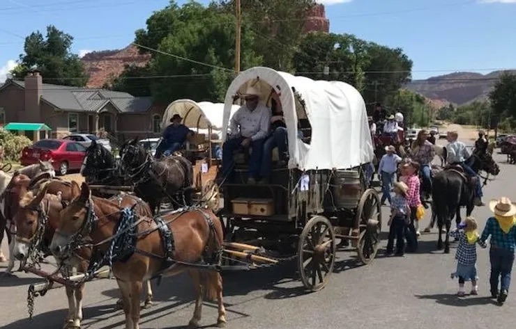 A man driving a horse-drawn carriage through a parking lot.