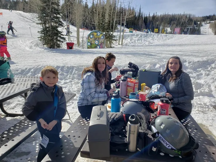 A family enjoying a day of snowboarding and hot beverages in the snow.