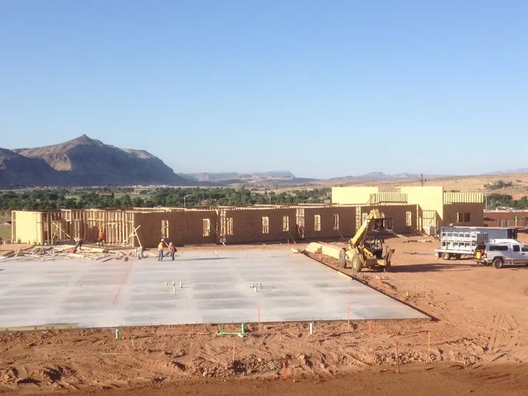 A large, open construction site with an unfinished building and a clear blue sky.