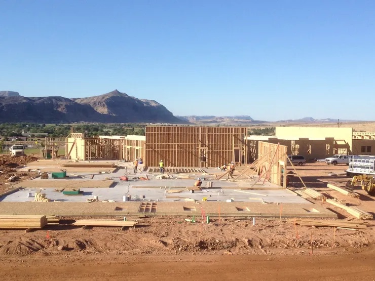 The image captures a bustling construction site under the clear blue sky, with a partially constructed building and various pieces of equipment visible.
