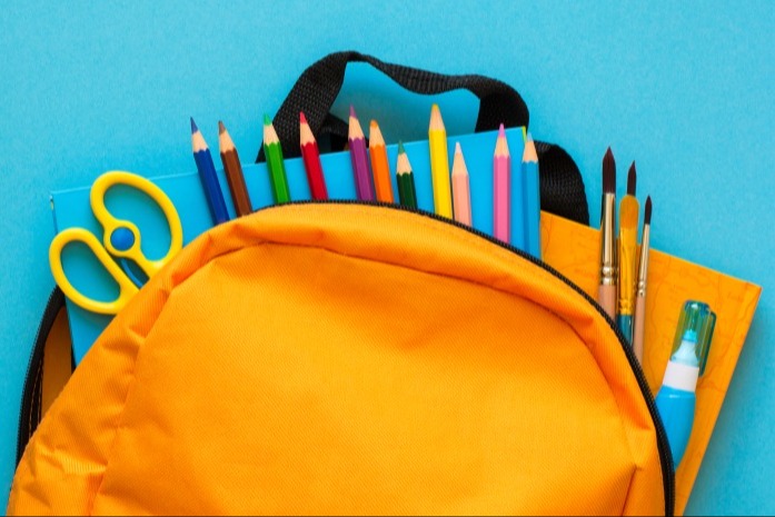 Orange backpack with colorful pencils, pens, scissors, and a highlighter on a blue background.