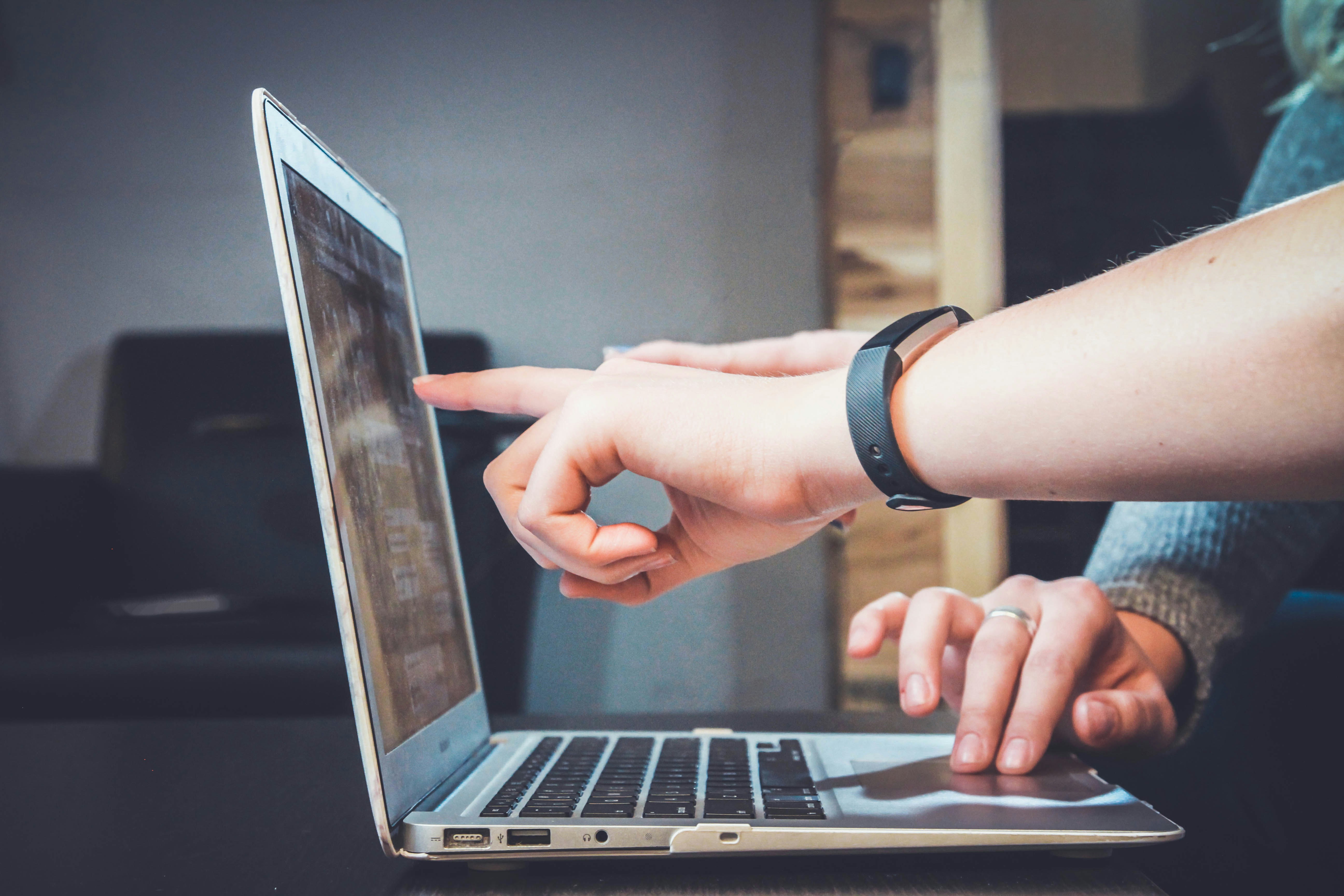 Hand pointing at a laptop computer screen