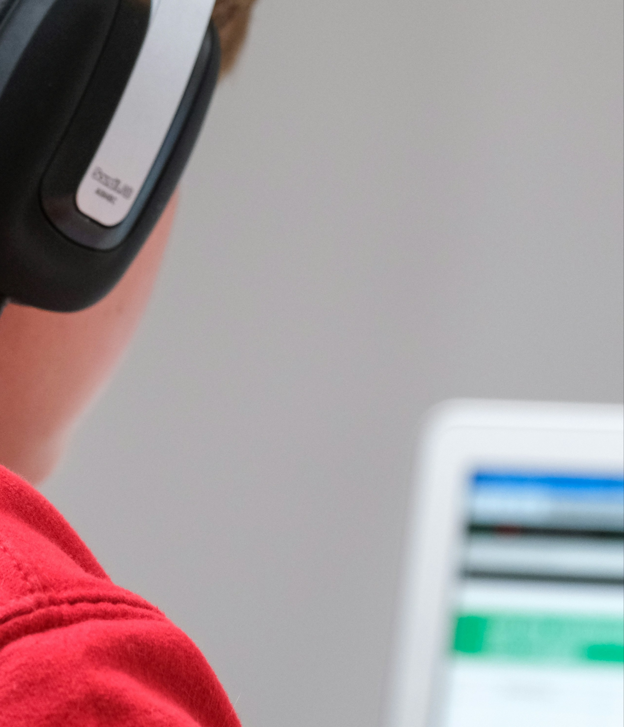 young boy sitting in front of a computer with headphones