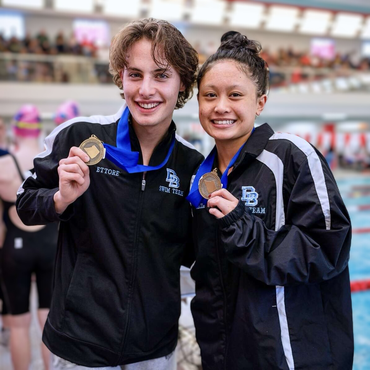 Two Daniel Boone student wearing and holding medals earned in swimming competitions