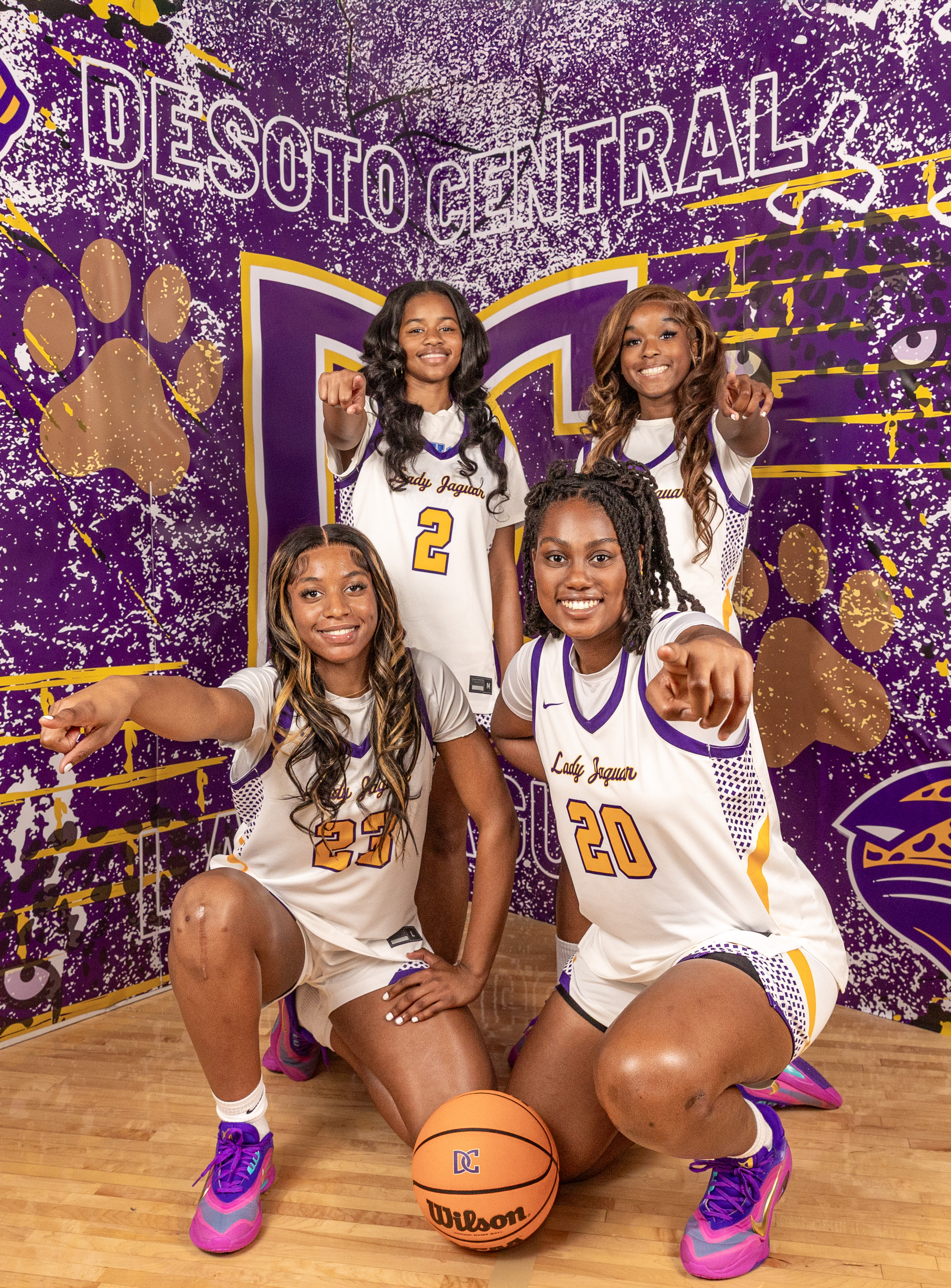 Two Lady Jags team members standing back to back on the basketball court