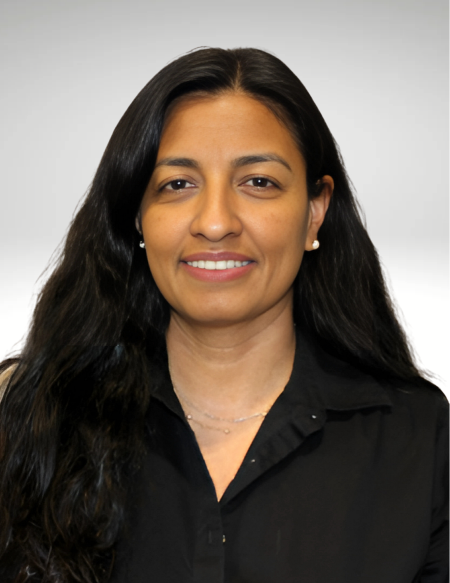 A woman with long black hair smiles softly while wearing a black collared shirt against a plain gray background. The tone is professional and approachable.