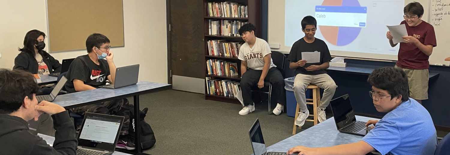 students in class with papers and computers