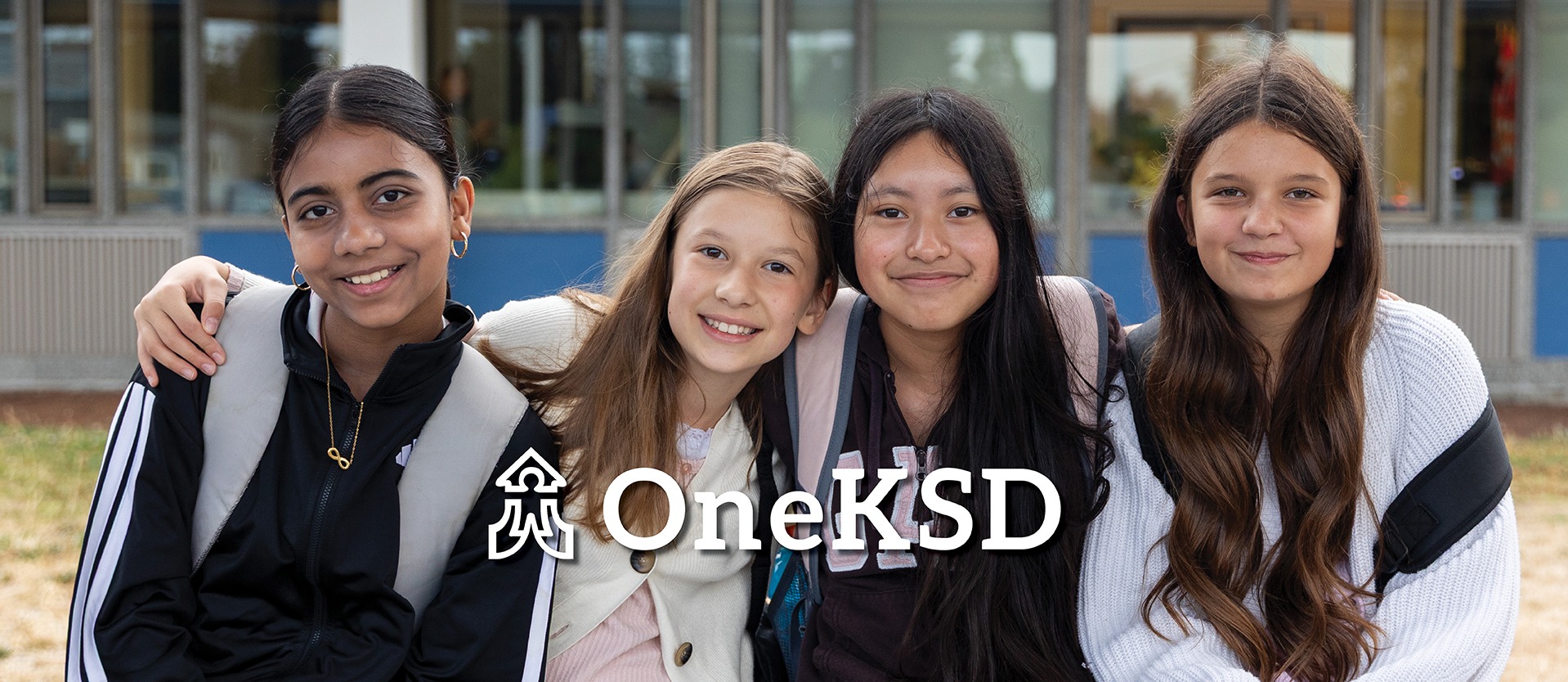 Four students in front of a school
