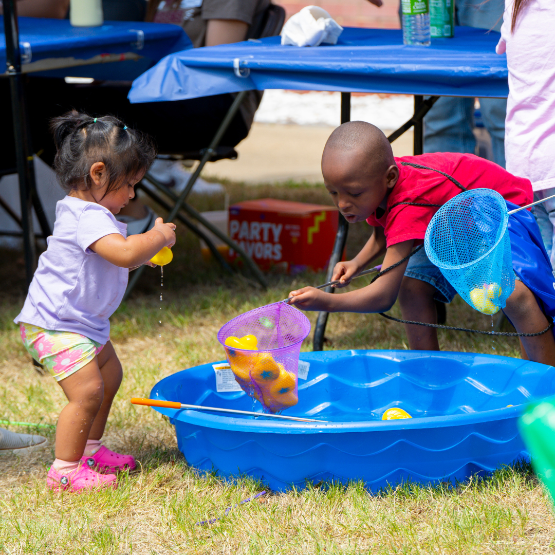 Photo of two children playing a fishing game in a kiddie pool at the 2024 Outdoor Expo Kids World