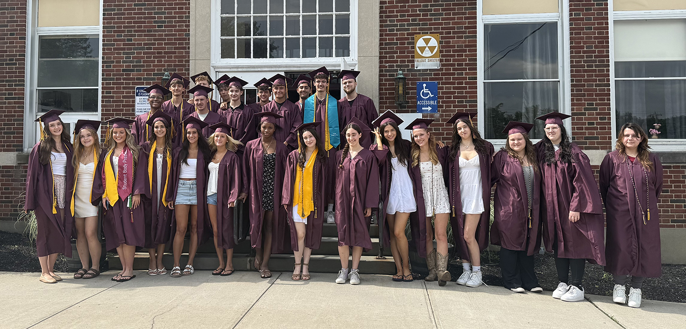Group of HS students in caps and gowns in front of Traver Primary