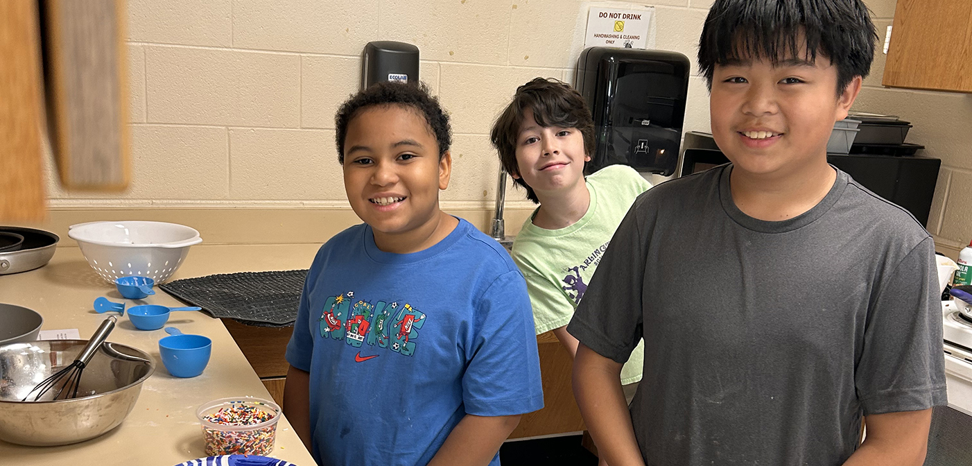 3 students in the kitchen for the first week of cooking for kids class of the summer kids program.