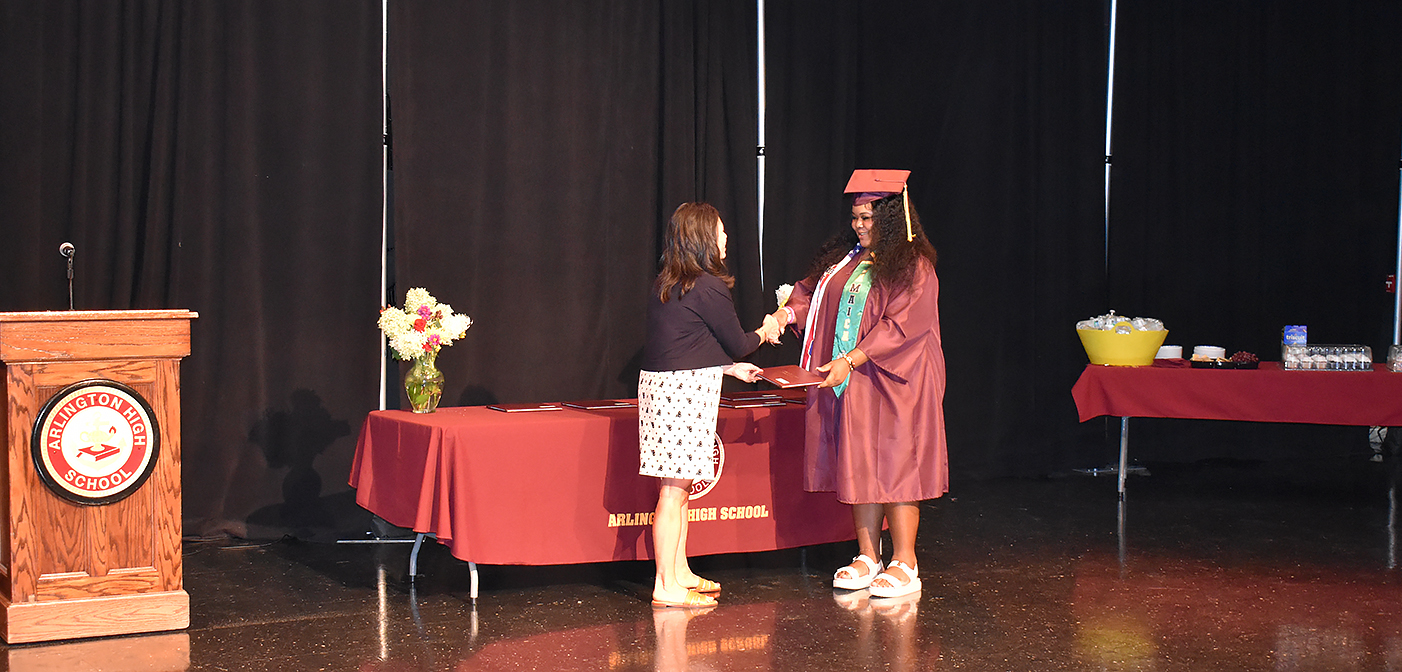 Young woman in cap and gown receiving diploma